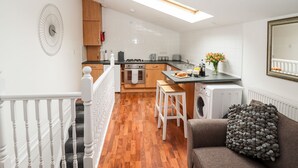 Eine moderne Küche mit Holzausstattung, einem eingebauten Backofen und einer Essecke mit einer Bank.