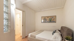 Une chambre à coucher avec un lit, une plante en pot et un tableau accroché au mur.