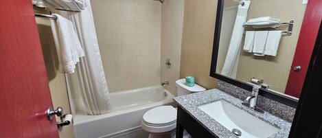 A bathroom with a bathtub, toilet, sink, and a mirror.