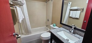 A bathroom with a bathtub, toilet, sink, and a mirror.