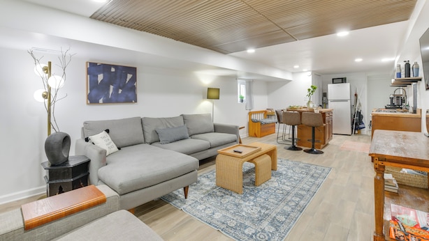 A modern living room with a grey sectional sofa, a wooden coffee table, and a blue patterned rug. - Logan Square Urban Oasis: 2 Mi to Local Hotspots! (Chicago)