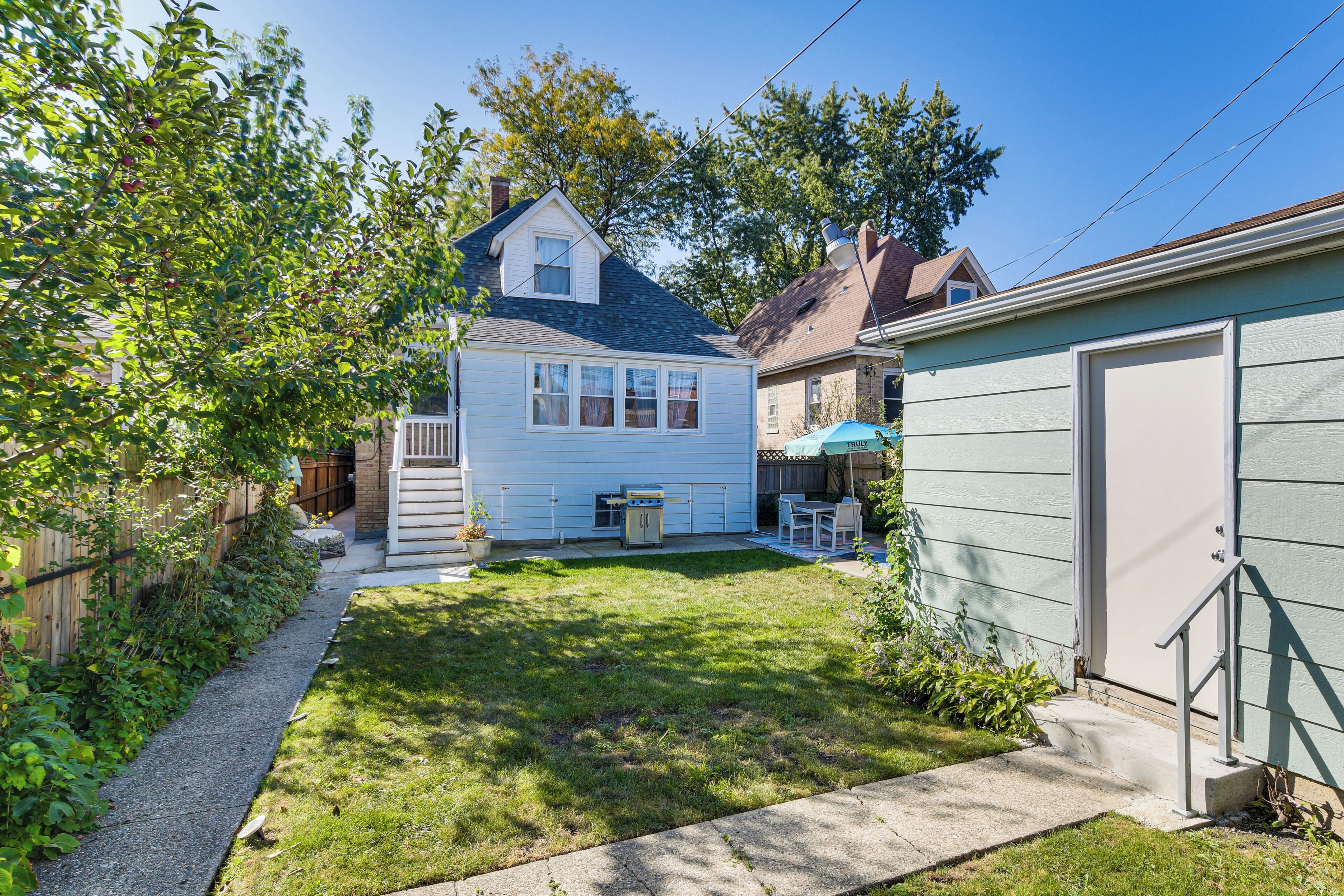 A residential backyard with a house, a barbecue grill, and a shed.