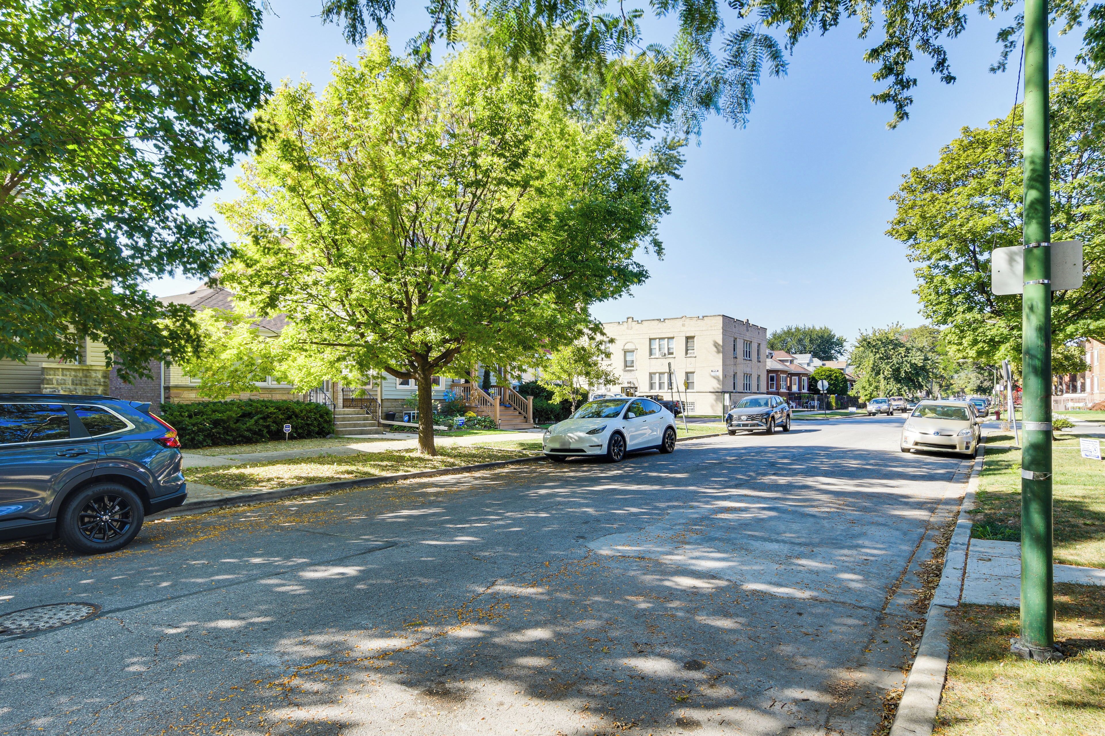 A street with parked cars, trees, and buildings.