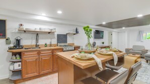 A modern kitchen with wooden cabinets, a central island, and a dining area with chairs. - Logan Square Urban Oasis: 2 Mi to Local Hotspots! (Chicago)