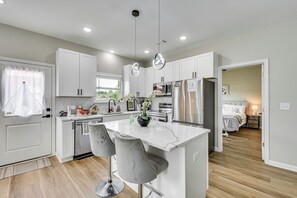 Une cuisine moderne avec des meubles blancs, des appareils en acier inoxydable et un îlot central doté de tabourets de bar.