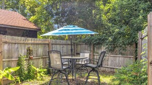 An outdoor patio with a table and chairs, a blue umbrella, and a wooden fence. - Cozy Spot - Perfect for Long Stays - Walk Downtown (Spartanburg)