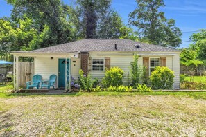 A single-story house with a covered porch, two blue chairs, and a small garden.