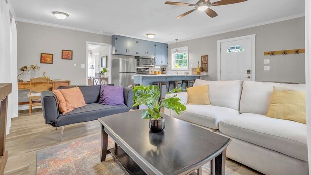 A modern living room with a sofa, coffee table, and a ceiling fan. - Cozy Spot - Perfect for Long Stays - Walk Downtown (Spartanburg)