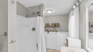 A compact bathroom with a shower, a toilet, a sink, and a washing machine. - Cozy Spot - Perfect for Long Stays - Walk Downtown (Spartanburg)