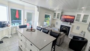 Una cocina moderna con una isla de mármol, comedor y chimenea.