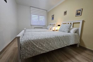 Een tweepersoonsbed met beddengoed met patroon, een nachtkastje met een lamp en een radiator.