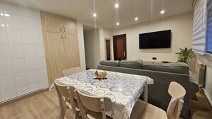 Uma sala de estar moderna com uma mesa de jantar, sofá e televisão.