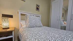 A bedroom with a bed, a nightstand, a lamp, a wardrobe, and a framed picture on the wall. - 1A111 Apartamento moderno de 3 dormitorios. (Gijón)