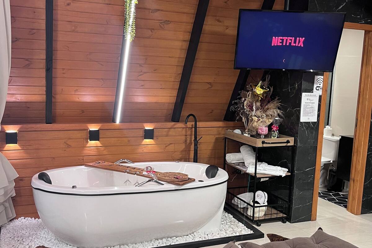 Ein modernes Badezimmer mit einer freistehenden Badewanne, einem Netflix-Schild und einer Holzablage mit Handtüchern.