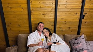 A couple relaxing on a sofa in a room with wooden walls and a small wooden table with a blue flame. - Miraflores Recanto (Imarui)