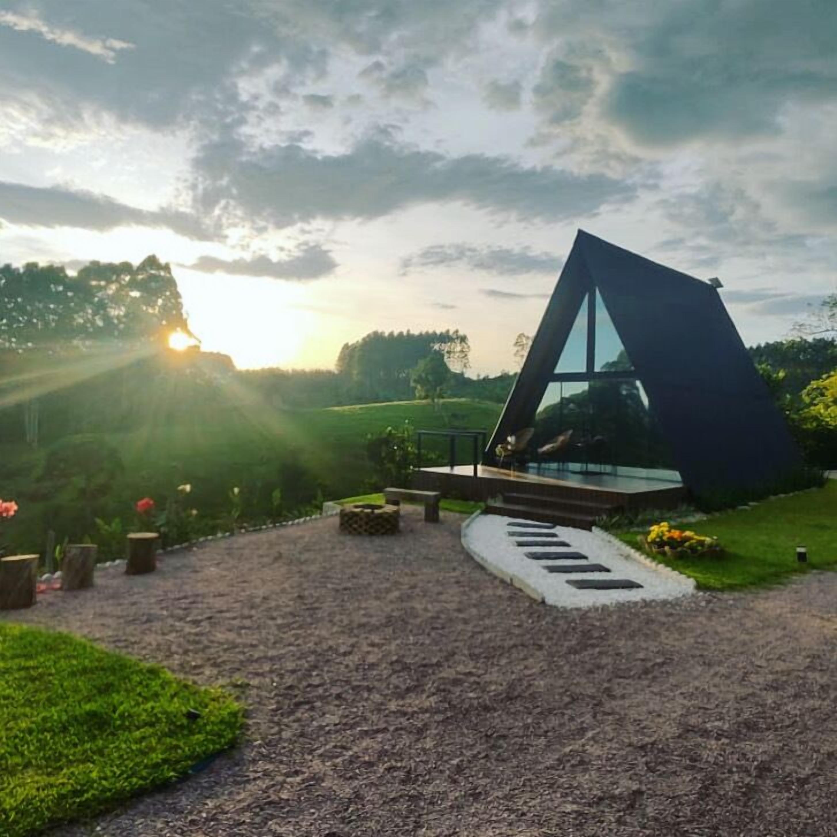 Un edificio moderno con techo triangular, rodeado por un jardín ajardinado con un sendero de grava que lleva a la entrada.