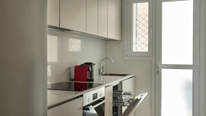 A compact kitchen with a built-in oven, a dishwasher, and a red coffee machine. - Athens Glow 2bd Apt in Ilisia (Athina)