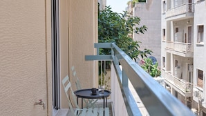 A balcony with a small table and chairs, a metal railing, and a view of adjacent buildings. - Athens Glow 2bd Apt in Ilisia (Athina)