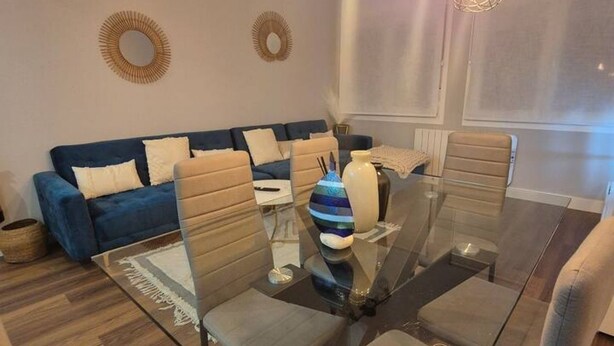 Una sala moderna con una mesa de vidrio, sofás y espejos decorativos en la pared.
