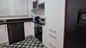 Cocina compacta con lavavajillas, microondas, horno y dispensador de agua.