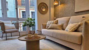 A living room with a beige sofa, a round coffee table, and a wicker chair.