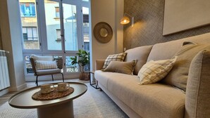 A living room with a beige sofa, a round coffee table, and a chair with cushions.
