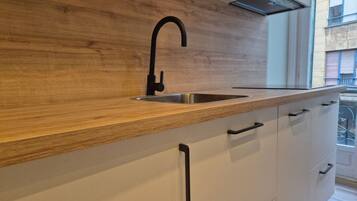 Een moderne keuken met een houten aanrecht, een zwarte kraan en witte kasten.