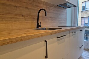 Una cocina moderna con encimera de madera, grifo negro y armarios blancos.