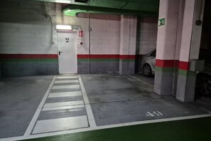 A parking garage with a white door marked '2' and a green exit sign. - 654A El Ático de la Alameda (Oviedo)