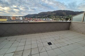 Ein möbelierter Balkon mit Blick auf Stadt und Hügellandschaft.