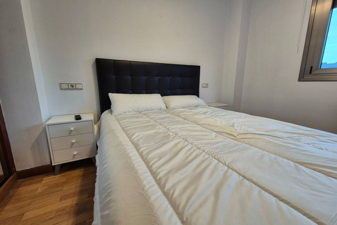 Un dormitorio con una cama grande, una mesita de noche y una ventana.