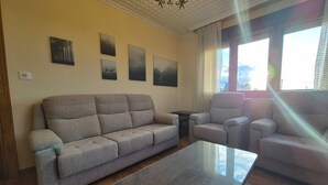 Un salon comprenant un canapé, des fauteuils, une table basse et des œuvres d’art murales.