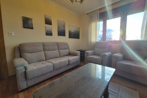 Un salon comprenant un canapé, des fauteuils, une table basse et des œuvres d’art murales.