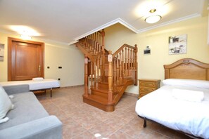 Un dormitorio con escalera de madera, dos camas individuales, un sofá y una mesita de noche.