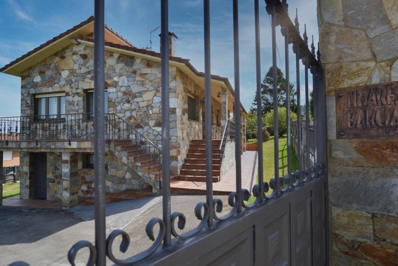 A stone house with a balcony, a staircase, and a wrought iron gate.