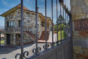 A stone house with a balcony, a staircase, and a wrought iron gate.