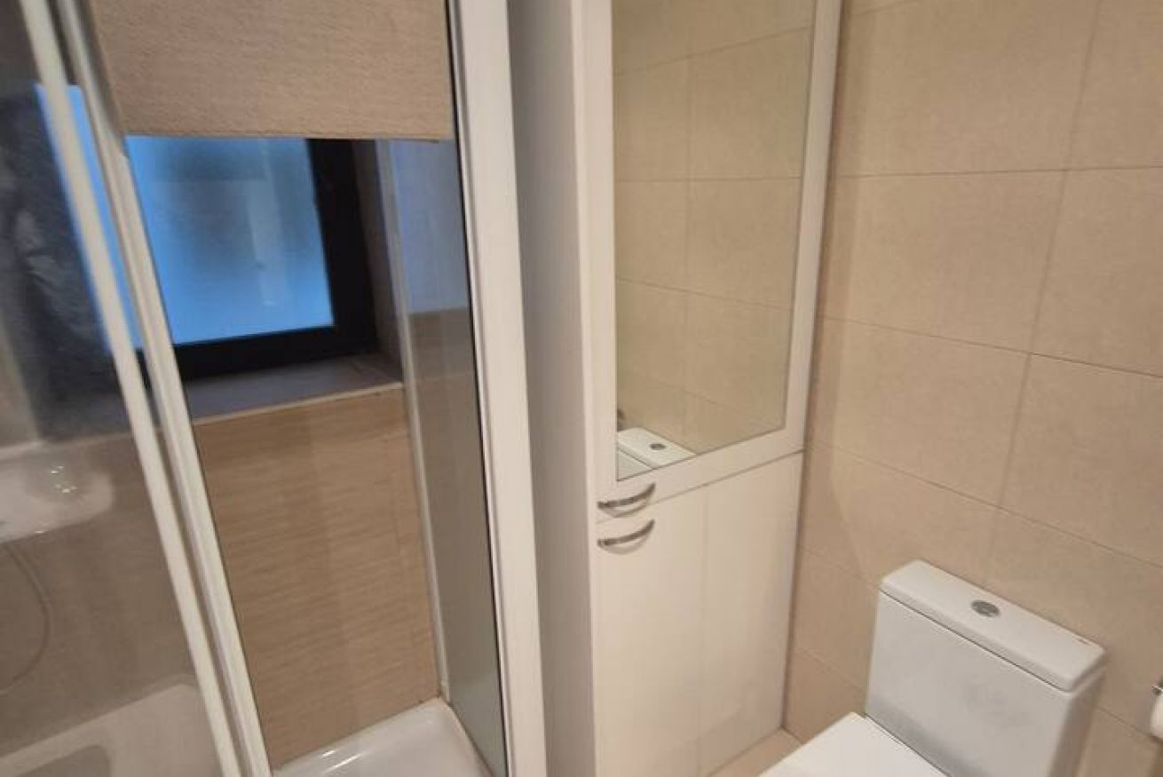 Een badkamer met toilet, douchecabine en spiegel.