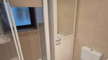 Een badkamer met toilet, douchecabine en spiegel.
