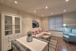 A modern living room with a glass dining table, a sofa set, a cabinet, and a large window. - 1A150 Apartamento c éntrico en Gijón (Gijón)