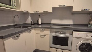 A compact kitchen with a built-in microwave, oven, and washing machine. - 1A150 Apartamento céntrico en Gijón (Gijón)