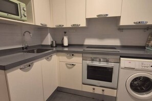 A compact kitchen with a built-in microwave, oven, and washing machine. - 1A150 Apartamento céntrico en Gijón (Gijón)