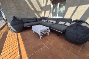 Ein Ecksofa mit Sitzsäcken auf einer gefliesten Terrasse.
