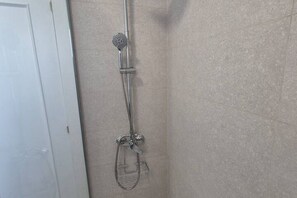 Une douche équipée d’un pommeau de douche à main et d’un flexible à main.