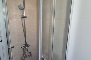 Une douche équipée d’un pommeau de douche à main et d’un robinet fixé au mur.