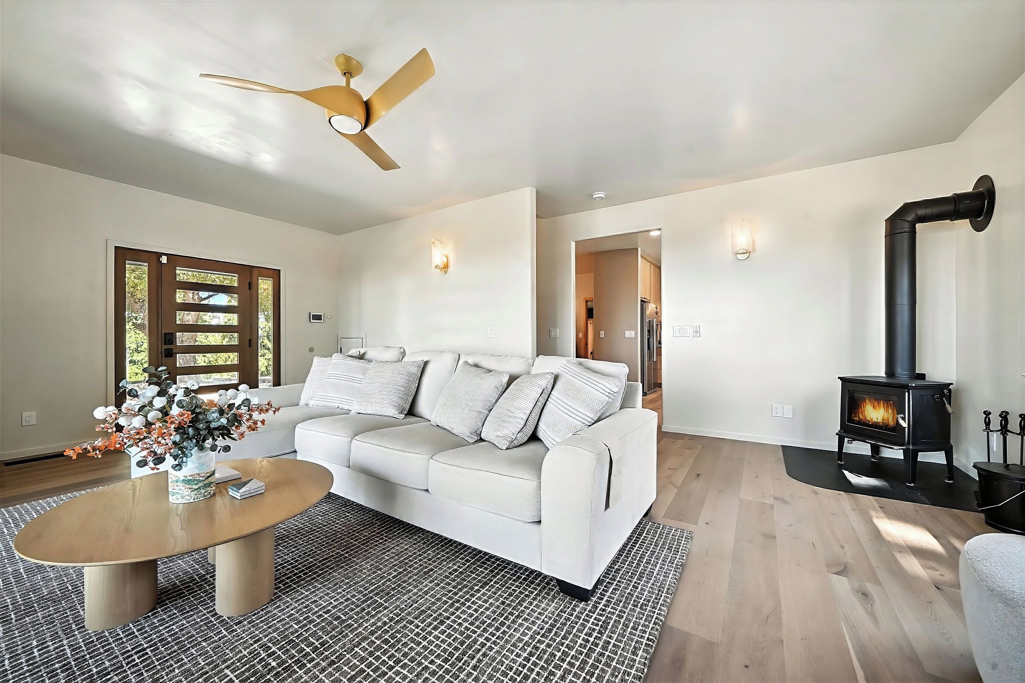 Ein modernes Wohnzimmer mit einem weißen Sofa, einem Couchtisch, einem Kamin und einem Deckenventilator.