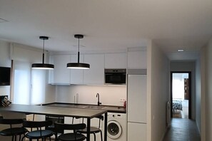 A modern kitchen with a central island, built-in appliances, and pendant lighting. - 803A Bonito apartamento en Luarca (Valdés)