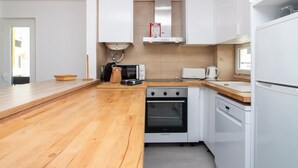 Een moderne keuken met houten aanrechtbladen, een inbouwoven, een magnetron en witte kasten.