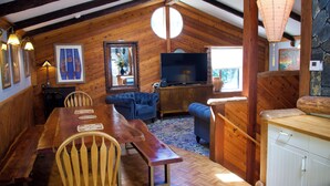 A cozy, wooden-furnished dining area with a long table, benches, and a television.