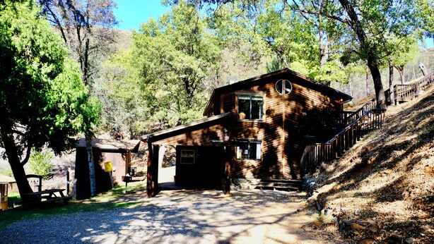 A rustic cabin with a wooden exterior, a porch, and a small attached structure.