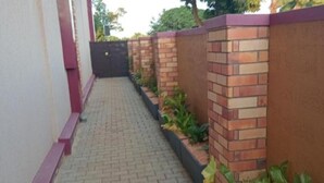 A narrow paved walkway flanked by brick walls and a gated entrance. - Stunning Studio Apartment on Entebbe that is fully furnished and accessible (Namulanda)